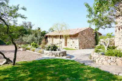 a stone house with a garden and a stone walkway at Domaine Pozzo di Mastri hôtel & spa in Figari