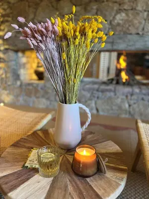 a vase of flowers and a candle on a table at Domaine Pozzo di Mastri hôtel & spa in Figari