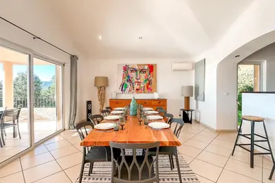 a dining room with a large wooden table and chairs at Villa Golfo Di Sogno in Porto-Vecchio