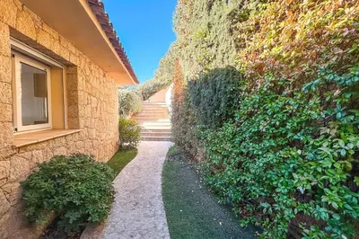 a stone wall with a walkway next to a building at Villa Golfo Di Sogno in Porto-Vecchio