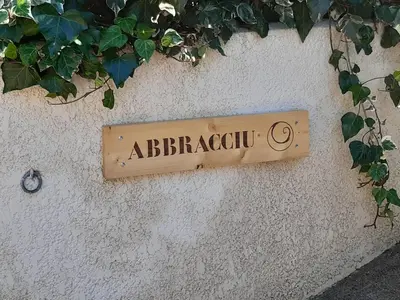 a sign on the side of a wall with plants at Villa Abbracciu climatisée avec piscine chauffée et vue mer in Pietrosella