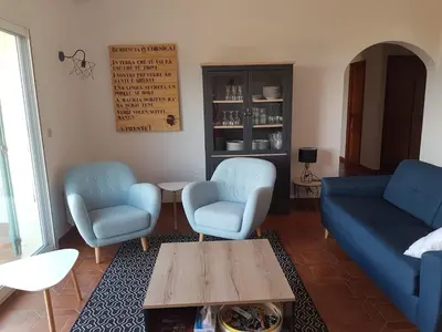a living room with two blue chairs and a table at Villa Abbracciu climatisée avec piscine chauffée et vue mer in Pietrosella