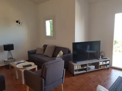 a living room with a couch and a flat screen tv at Villa Abbracciu climatisée avec piscine chauffée et vue mer in Pietrosella