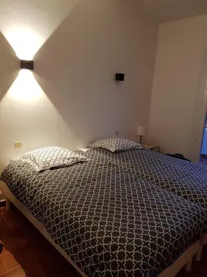 a bedroom with a bed and a light on the wall at Villa Abbracciu climatisée avec piscine chauffée et vue mer in Pietrosella