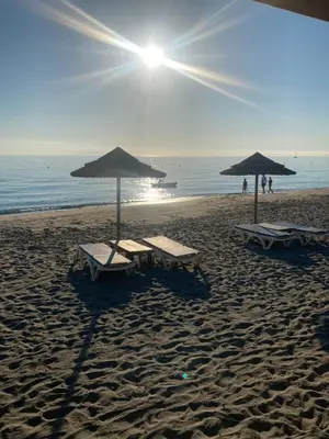 two lounge chairs and umbrellas on a beach at Maison bord de mer en Corse in Borgo