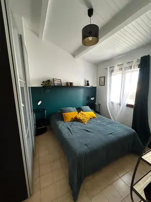 a bedroom with a bed with blue sheets and yellow pillows at Maison bord de mer en Corse in Borgo