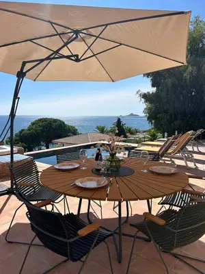 a wooden table with chairs and an umbrella at Casa Raphael in Ajaccio