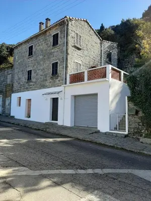 an old stone building with a garage in front of it at Grande Maison de Village in Sollacaro