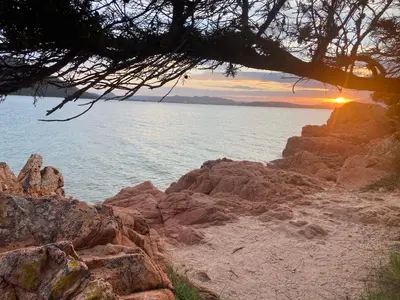 a sunset on the shore of a rocky beach at Mini villa avec jardin Cala Rossa - Porto Vecchio in Lecci