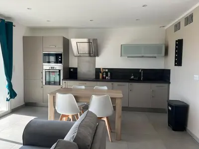 a kitchen with a table and white chairs in a room at Appartement proche de la plage in Santa-Lucia-di-Moriani