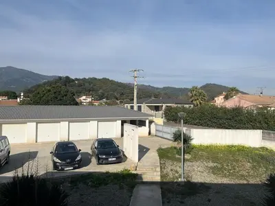two cars parked in a parking lot in front of a building at Appartement proche de la plage in Santa-Lucia-di-Moriani