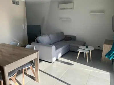 a living room with a couch and a table and chairs at Appartement proche de la plage in Santa-Lucia-di-Moriani