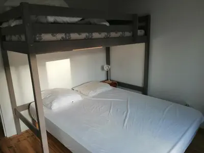 a bedroom with two bunk beds with white sheets at Maison bord de mer climatisée en Corse in Poggio-Mezzana