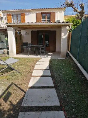 a backyard with a table and a house at Maison bord de mer climatisée en Corse in Poggio-Mezzana