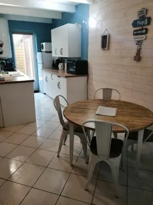 a kitchen with a wooden table and chairs in a room at Maison bord de mer climatisée en Corse in Poggio-Mezzana