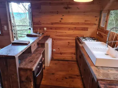 a kitchen in a log cabin with a sink and a stove at Cabane avec Piscine in Sartène