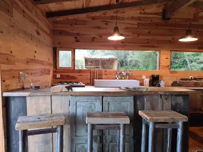 a kitchen with wooden cabinets and bar stools at Cabane avec Piscine in Sartène
