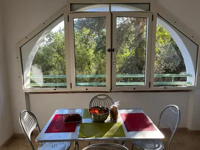 a table and chairs in front of a large window at Appartement Jardin de la Mer in Linguizzetta