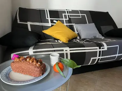 a cake on a table next to a couch at Appartement Jardin de la Mer in Linguizzetta