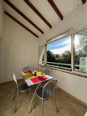 a dining room with a table and chairs and a window at Appartement Jardin de la Mer in Linguizzetta
