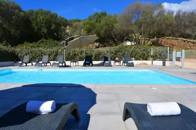 a swimming pool with chairs and an umbrella at Les Terrasses Du Grand Large in Porto Pollo