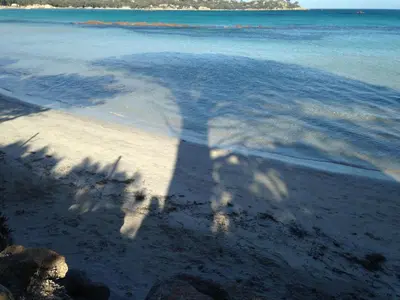 a shadow of a person taking a picture of the ocean at Les Terrasses Du Grand Large in Porto Pollo