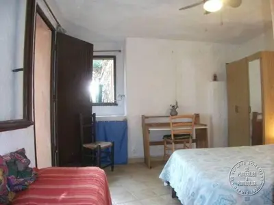 a bedroom with a bed and a desk and a table at Villa Pierre Vergerie in Cargèse