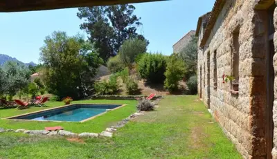 a yard with a swimming pool and a stone building at Le Hameau de Saparale in Sartène