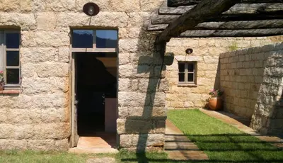 a stone building with a door and a yard at Le Hameau de Saparale in Sartène