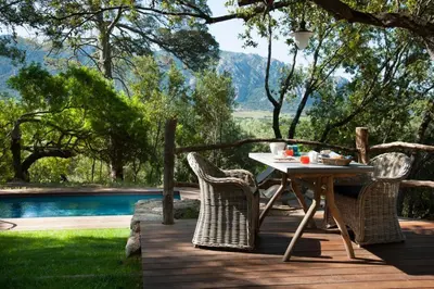 a table and chairs on a deck next to a pool at Le Hameau de Saparale in Sartène