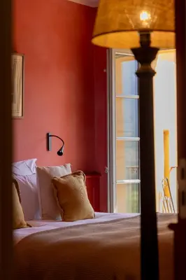 a bedroom with a bed with a lamp and a window at Le Hameau de Saparale in Sartène