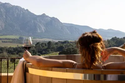 a woman sitting on a barrel with a glass of wine at Le Hameau de Saparale in Sartène