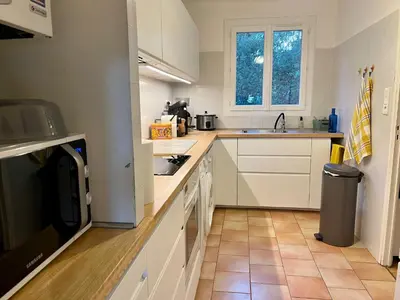 a kitchen with white cabinets and a tile floor at Villa Nausicaa in Pietrosella