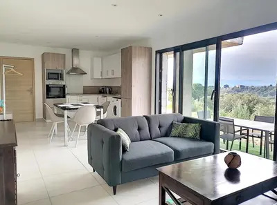 a living room with a blue couch and a kitchen at Bas de villa contemporaine avec vue dégagée in Alata