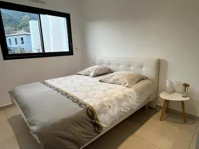 a bed in a bedroom with a window and a table at Bas de villa contemporaine avec vue dégagée in Alata