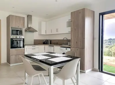 a kitchen with a table and chairs in a kitchen at Bas de villa contemporaine avec vue dégagée in Alata