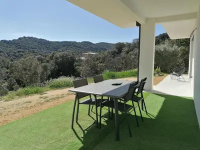 a black table and chairs on the back porch of a house at Bas de villa contemporaine avec vue dégagée in Alata