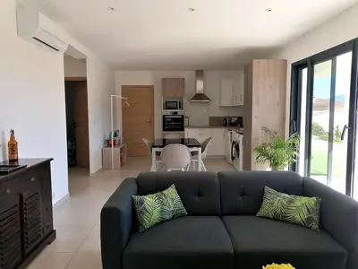 a living room with a couch and a kitchen at Bas de villa contemporaine avec vue dégagée in Alata