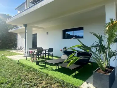 a white house with a patio with a table and chairs at Bas de villa contemporaine avec vue dégagée in Alata