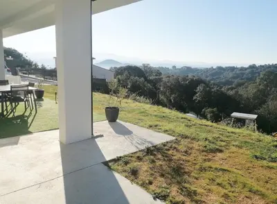 a porch with a table and a view of a field at Bas de villa contemporaine avec vue dégagée in Alata