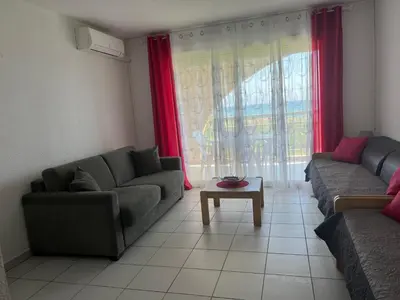 a living room with two couches and a table at Appart bord de mer avec piscine in San-Nicolao