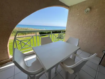 a table and chairs on a balcony with a view of the ocean at Appart bord de mer avec piscine in San-Nicolao