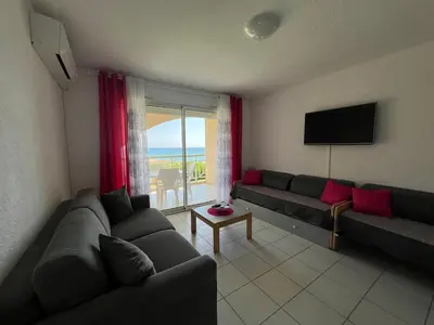 a living room with two couches and a television at Appart bord de mer avec piscine in San-Nicolao