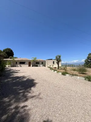 a gravel driveway with a building in the background at Villa de Luxe avec Piscine à débordement chauffée à Porticcio in Porticcio