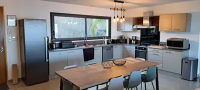a kitchen with a wooden table with chairs around it at Villa de Luxe avec Piscine à débordement chauffée à Porticcio in Porticcio