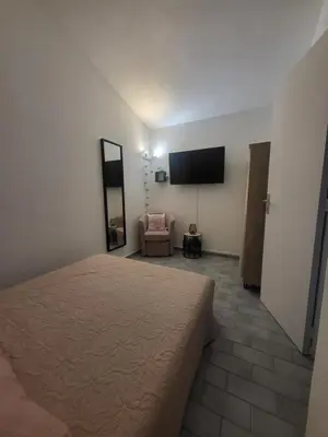 a bedroom with a bed and a chair and a flat screen tv at Porto Vecchio - Résidence RIVIERA- Villa Lecci in Lecci