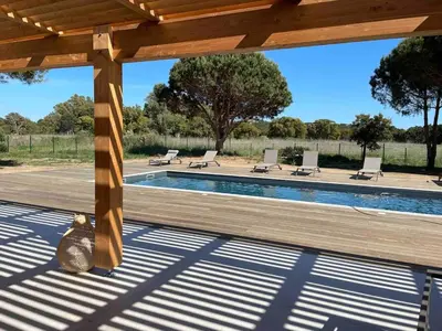 a wooden pergola with a pool and lounge chairs at Villa Casa di sognu in Lecci