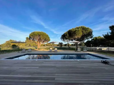 a swimming pool with benches and umbrellas in a park at Villa Casa di sognu in Lecci