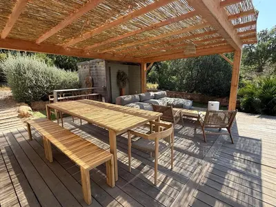 a patio with a wooden table and chairs and a pergola at Porto-Vecchio - Lecci Lodge in Lecci