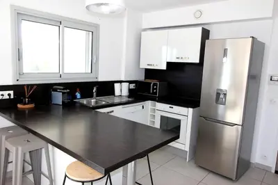 a kitchen with a black counter and a stainless steel refrigerator at T2 centre-ville de Porto-Vecchio in Porto-Vecchio